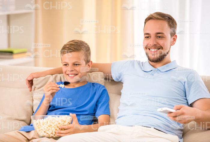 Father With Son Watching Movie And Eating Popcorn Stock Photo