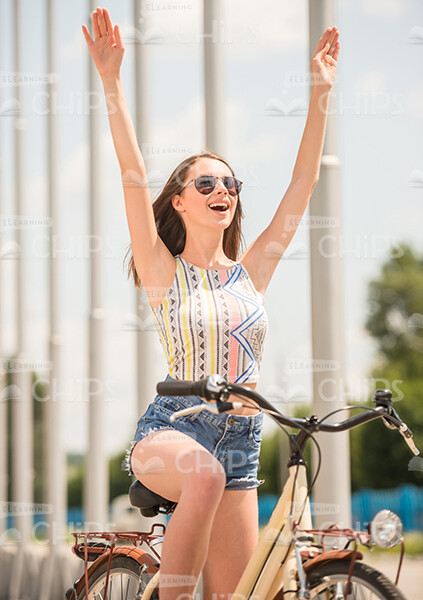 Young Girk Riding On Bike While Raising Both Hands Up Stock Photo