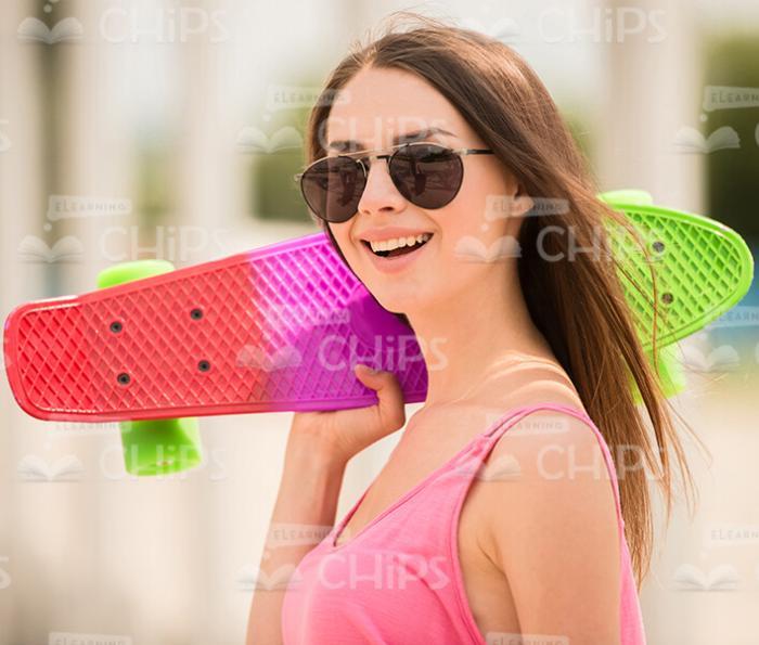 Woman Holding Skateboard On Shoulder Stock Photo