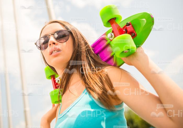 Young Girl Holding Skateboard Behind Her Shoulders