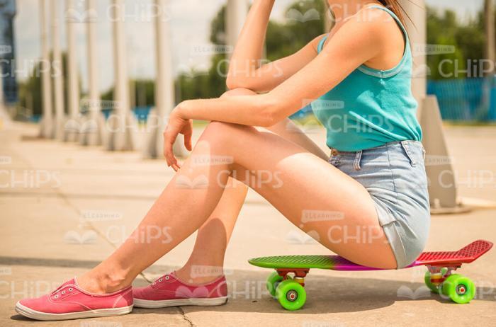 Girl Sitting On Skateboard Stock Photo
