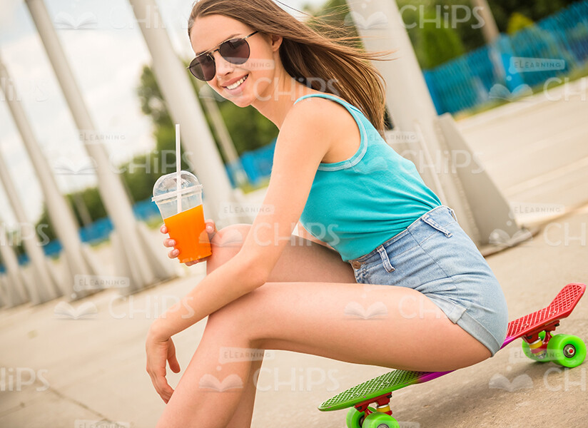 Smiling Girl Sits On Skateboard And Holds Cup With Juice Stock Photo Smiling Girl Sits On Skateboard And Holds Cup With Juice Stock Photo