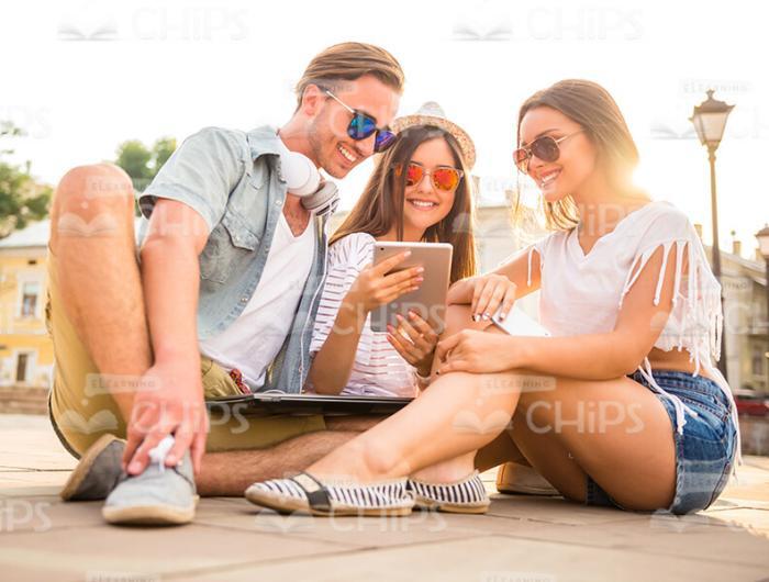 Young People Sitting On Ground And Using Tablet Stock Photo