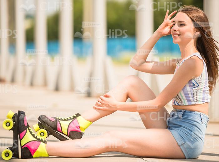 Girl In Roller Skates Sitting On Ground Stock Photo