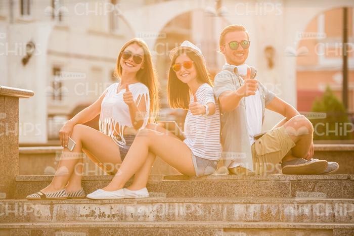 Young People Sitting On Stairs And Showing Thumbs Up Stock Photo