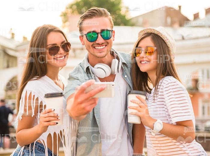 People Holding Coffee Cups And Looking At Smartphone's Screen Stock Photo