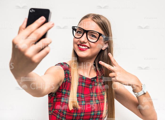 Girl Showing The Peace Gesture While Taking Selfie Stock Photo