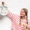 Young Girl Holding Clock And Showing Thumb Up Gesture Stock Photo