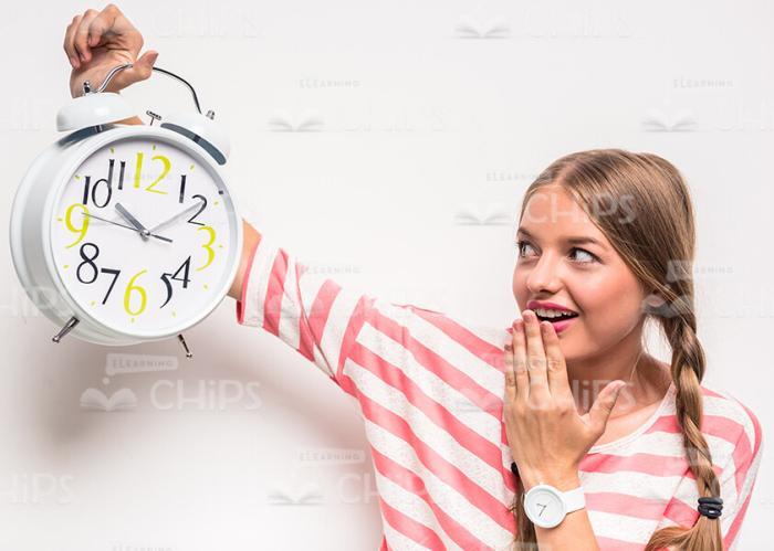 Surprised Young Girl Holding Clock And Looking On Them
