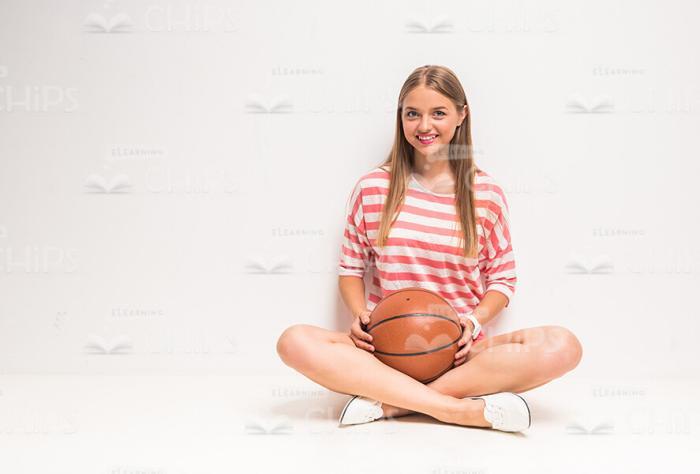 Smiling Girl Sitting On Floor With Her Basketball Stock Photo