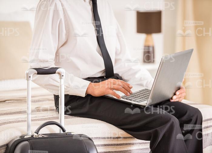 Businessman Using Laptop While Sitting On Hotel's Bad Stock Photo