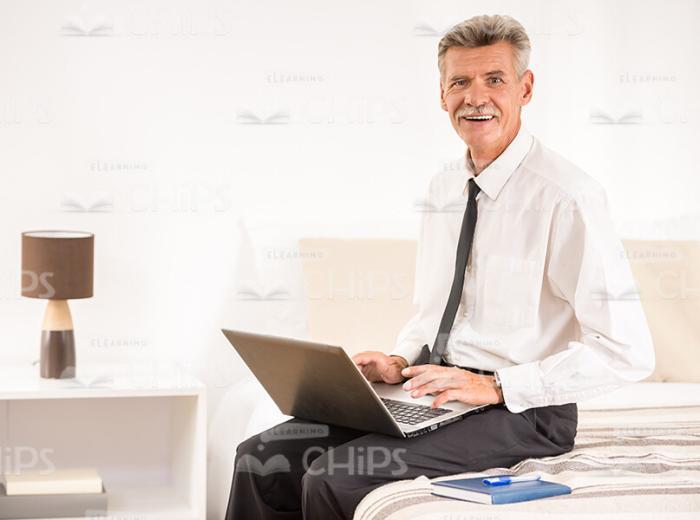 Focused Aged Businessman With Laptop On His Lap Stock Photo