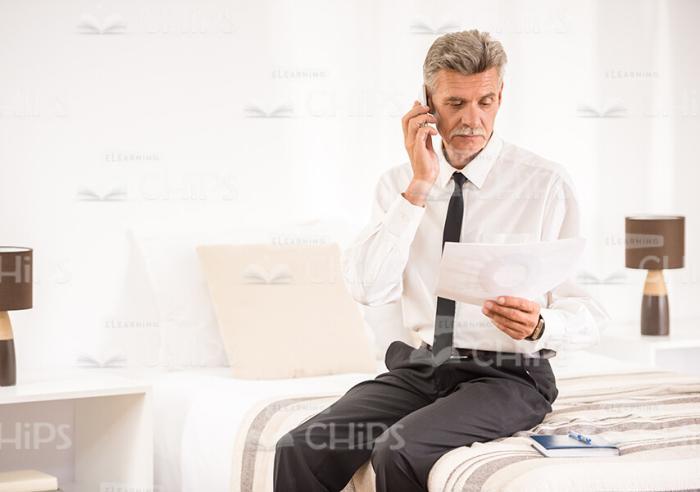 Old Business Man Talking On Phone At Hotel Room Stock Photo