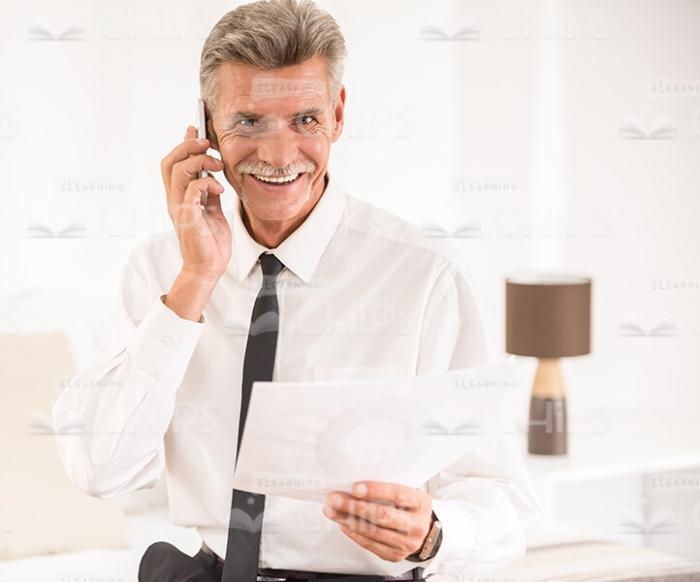 Smiling Old Businessman Talking The Phone And Holding Papers Stock Photo