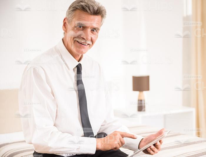 Smiling Aged Businessman Using Tablet Stock Photo