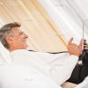 Aged Businessman Resting On Bed And Using Tablet Profile View Stock Photo