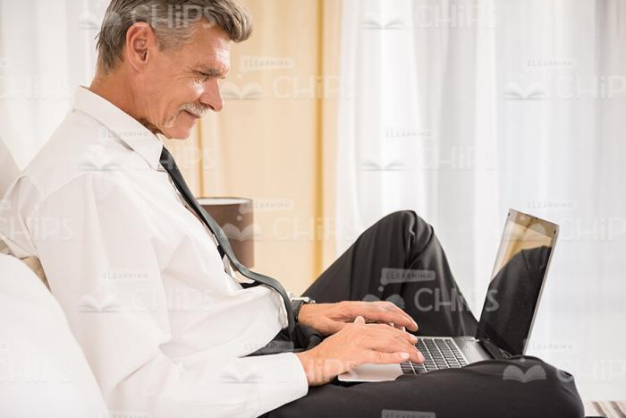 Handsome Businessman Working On Laptop While Lying In Bed Stock Photo