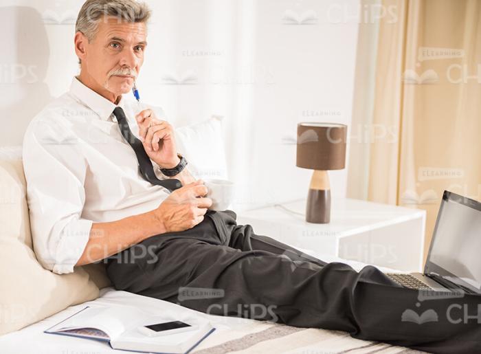 Aged Businessman Resting On Bed Stock Photo