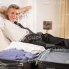 Smiling Aged Man With Packed Suitcase Stock Photo
