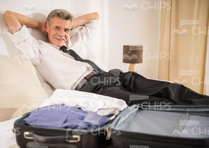Smiling Aged Man With Packed Suitcase Stock Photo