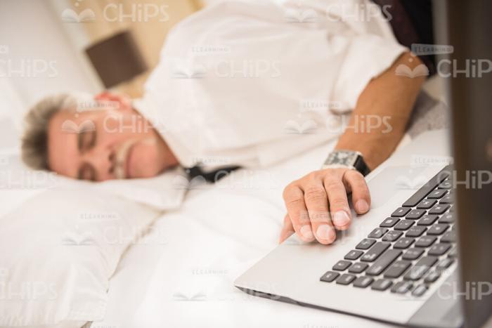 Bored Old Man Sleeping While Holding Hand On Laptop Stock Photo
