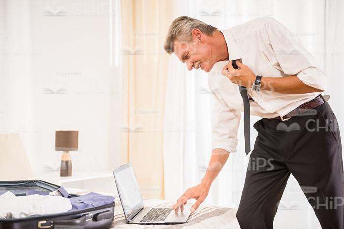 Aged Businessman Dressing And Using Laptop Stock Photo