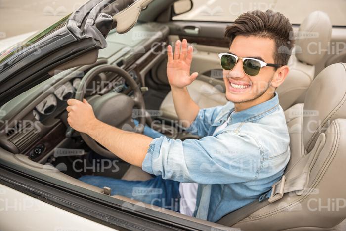 Half-Turned Man Driving Vehicle And Waving Hand Stock Photo