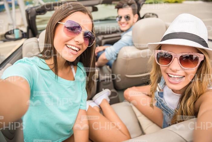 Two Pretty Girls Turn And Smile In Camera While Drive In Convertible Car Stock Photo