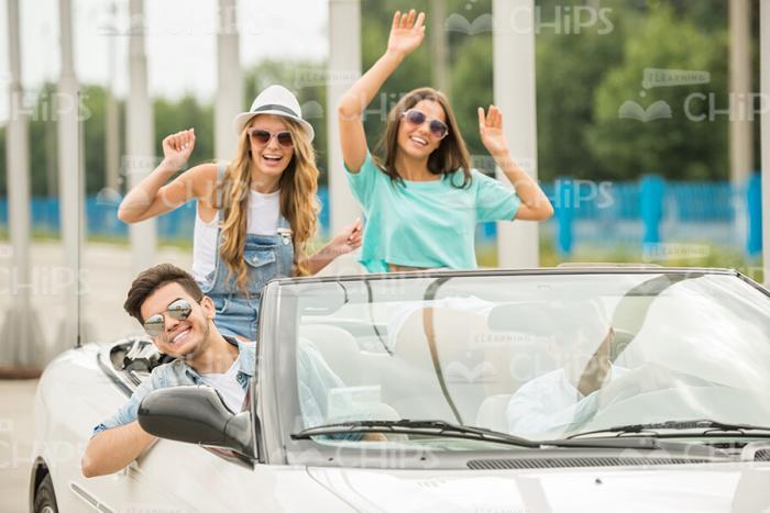 Excited Young People Sitting In Convertible Vehicle Stock Photo