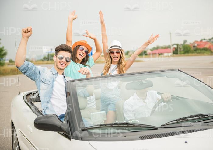 Excited Friends In Convertible Car Raising Hands Up Stock Photo