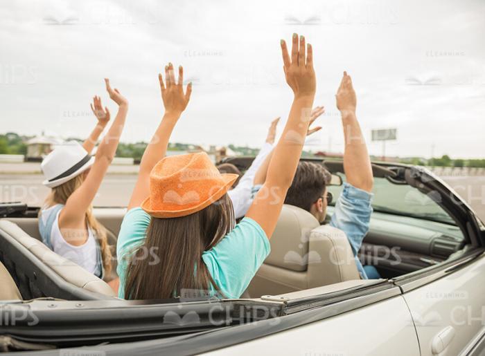 Four Young Fellows Raising Hands Up In Convertible Car Stock Photo