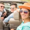 Pretty Young Girl Wearing Sunglasses And Sitting In Convertible Car With Her Friends Stock Photo