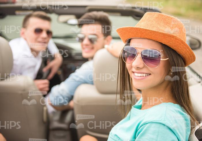 Pretty Young Girl Wearing Sunglasses And Sitting In Convertible Car With Her Friends Stock Photo