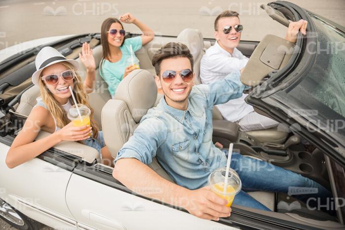 Four Friends In Cabriolet Car Drinking Juice Stock Photo