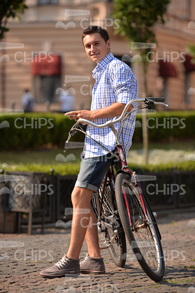 Casually Dressed Young Man Leaning On His Bicycle Stock Photo