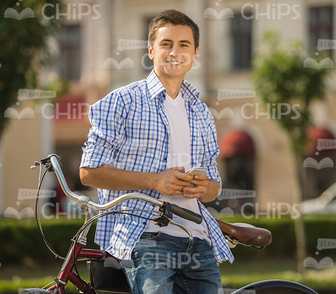 Smiling Man With Mobile Phone Leans On Bicycle Stock Photo