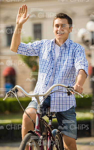Smiling Man Riding Bicycle And Waving Hand Stock Photo