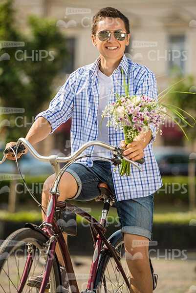Happy Man With Bouquet Of Flowers Sitting On Bike Stock Photo
