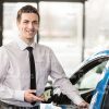 Car Salesman Standing Next To Blue Vehicle Stock Photo