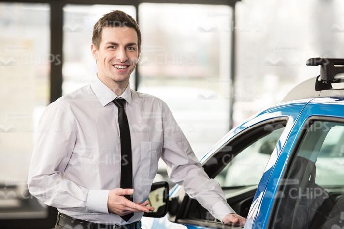 Car Salesman Standing Next To Blue Vehicle Stock Photo