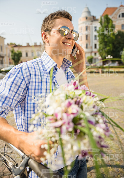 Smiling Man Holding Bouquet Of Flowers And Talking On Mobile Phone Stock Photo