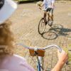 Woman Riding On Bike To Her Friend With Bouquet Stock Photo