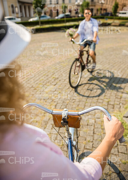 Woman Riding On Bike To Her Friend With Bouquet Stock Photo