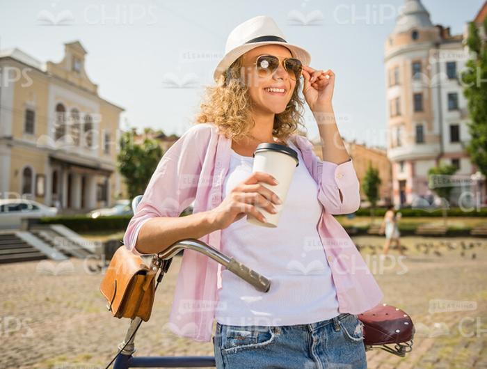 Woman Leans On Bike While Drinks Coffee Stock Photo