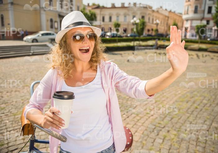 Young Woman With Coffee Waving Hand Stock Photo