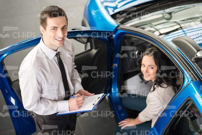 Car Sales Manager Helping Young Woman To Choose New Car Stock Photo