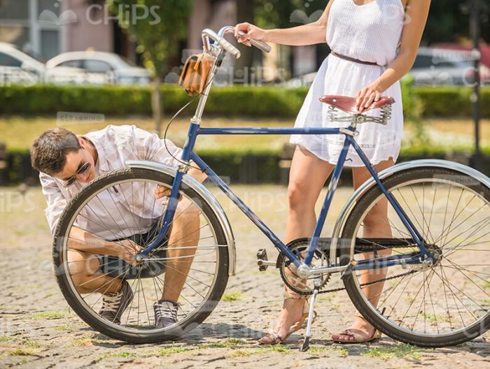 Young Man Repairing Her Girlfriend's Bike Stock Photo