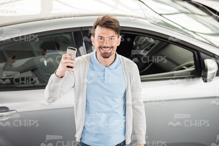 Young Man With Mobile Phone At Car Showroom Stock Photo