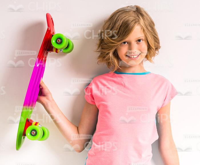 Smiling Little Girl Holding Skateboard With Her Right Hand Stock Photo