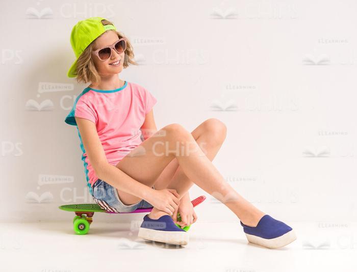 Young Female Skater Sitting On Her Skateboard Stock Photo